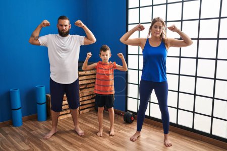 Photo for Family of three wearing sportswear at the gym relaxed with serious expression on face. simple and natural looking at the camera. - Royalty Free Image