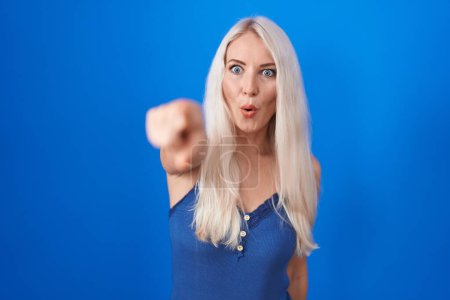 Téléchargez les photos : Femme blanche debout sur fond bleu pointant du doigt surpris devant, bouche ouverte expression étonnée, quelque chose sur le devant - en image libre de droit
