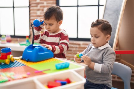Téléchargez les photos : Deux enfants jouant avec le jouet téléphonique assis sur la table à la maternelle - en image libre de droit