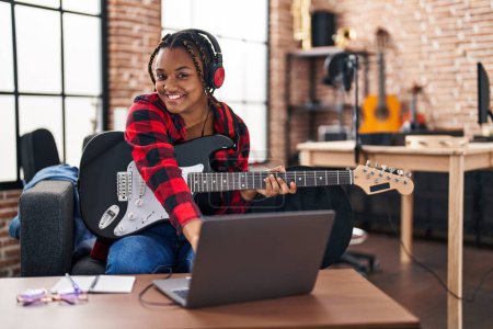 Foto de African american woman musician having online electrical guitar lesson at music studio - Imagen libre de derechos