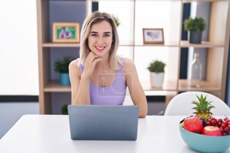 Téléchargez les photos : Young woman using laptop sitting on table at home - en image libre de droit