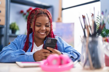 Photo for African american woman artist smiling confident using smartphone at art studio - Royalty Free Image