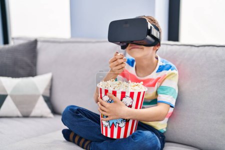 Foto de Blond child watching movie by virtual reality glasses at home - Imagen libre de derechos