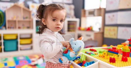 Photo for Adorable hispanic toddler holding elephant toy standing at kindergarten - Royalty Free Image
