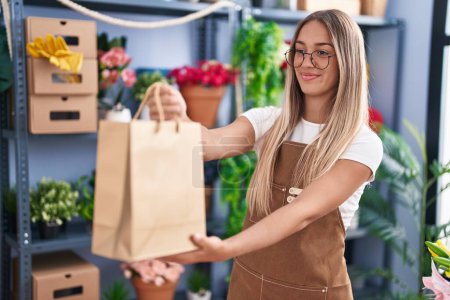 Photo for Young beautiful hispanic woman florist smiling confident holding shopping bag at flower shop - Royalty Free Image