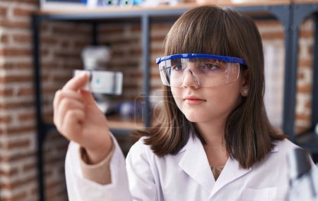 Photo for Adorable hispanic girl student looking sample at laboratory classroom - Royalty Free Image
