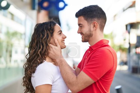 Téléchargez les photos : Jeune couple hispanique souriant confiant s'embrassant dans la rue - en image libre de droit