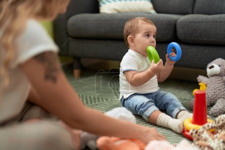 Téléchargez les photos : Adorable toddler bitting plastic hoop sitting on floor at home - en image libre de droit