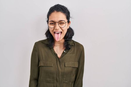 Téléchargez les photos : Hispanic woman with dark hair standing over isolated background sticking tongue out happy with funny expression. emotion concept. - en image libre de droit