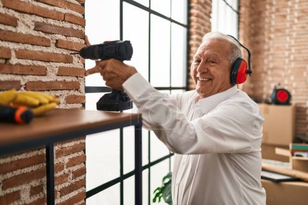 Photo for Senior man smiling confident drilling wall at new home - Royalty Free Image