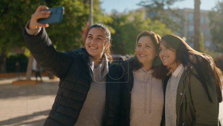 Photo for Mother and daugthers making selfie by the smartphone standing together at park - Royalty Free Image