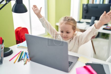 Foto de Adorable blonde girl student using laptop with cheerful expression at classroom - Imagen libre de derechos