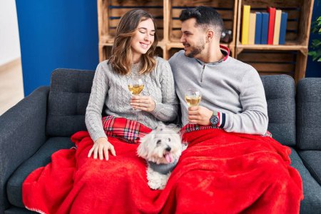 Téléchargez les photos : Grillé homme et femme avec champagne assis sur le canapé avec chien à la maison - en image libre de droit