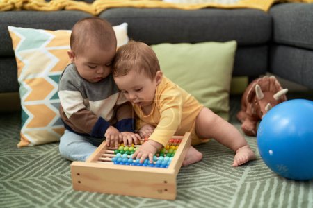 Photo for Two toddlers playing with abacus sitting on floor at home - Royalty Free Image