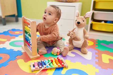 Photo for Adorable hispanic toddler playing with abacus sitting on floor at kindergarten - Royalty Free Image