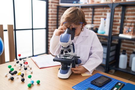 Photo for Adorable caucasian boy student using microscope at classroom - Royalty Free Image