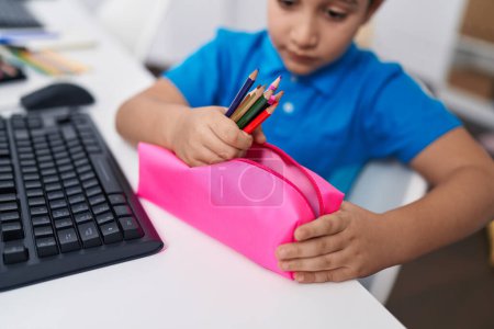 Photo for Adorable hispanic boy student holding pencil of case at classroom - Royalty Free Image
