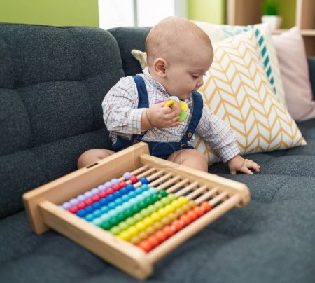Photo for Adorable caucasian baby playing with abacus sitting on sofa at home - Royalty Free Image