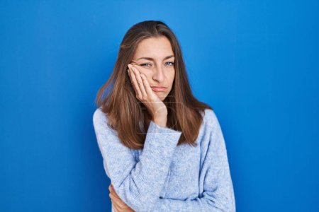 Photo for Young woman standing over blue background thinking looking tired and bored with depression problems with crossed arms. - Royalty Free Image