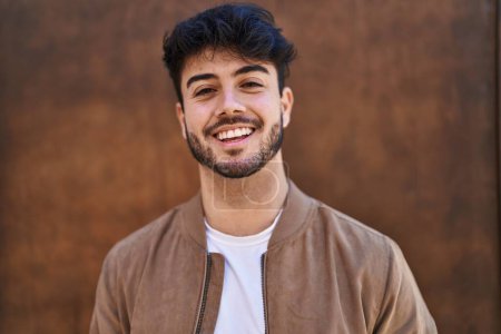 Téléchargez les photos : Young hispanic man smiling confident standing over brown isolated background - en image libre de droit