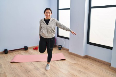 Photo for Young hispanic woman smiling confident stretching at sport center - Royalty Free Image