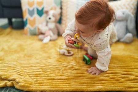Photo for Adorable redhead toddler playing with car toy sitting on sofa at home - Royalty Free Image