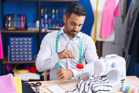 Photo for Young hispanic man tailor holding pin at sewing studio - Royalty Free Image