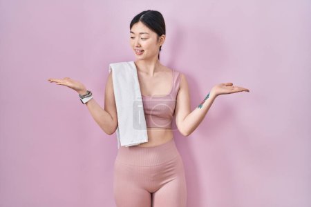 Photo for Chinese young woman wearing sportswear and towel smiling showing both hands open palms, presenting and advertising comparison and balance - Royalty Free Image