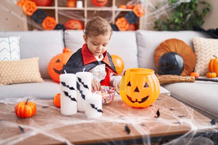 Téléchargez les photos : Adorable garçon caucasien ayant fête d'Halloween tenant des bonbons à la maison - en image libre de droit