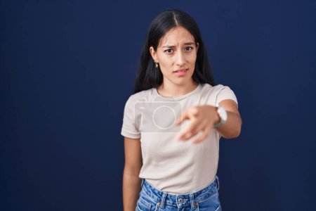 Foto de Young hispanic woman standing over blue background pointing displeased and frustrated to the camera, angry and furious with you - Imagen libre de derechos