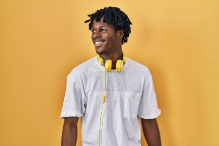 Téléchargez les photos : Young african man with dreadlocks standing over yellow background smiling looking to the side and staring away thinking. - en image libre de droit