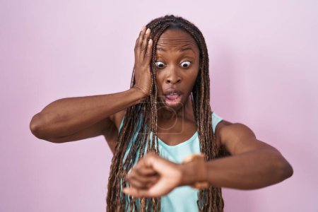 Téléchargez les photos : African american woman standing over pink background looking at the watch time worried, afraid of getting late - en image libre de droit