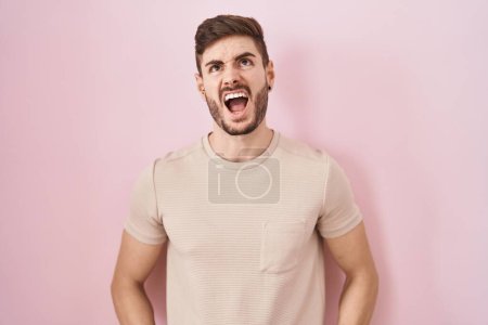 Téléchargez les photos : Hispanic man with beard standing over pink background angry and mad screaming frustrated and furious, shouting with anger. rage and aggressive concept. - en image libre de droit