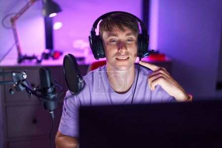 Téléchargez les photos : Blanc blond homme jouer à des jeux vidéo souriant heureux pointant avec la main et le doigt - en image libre de droit