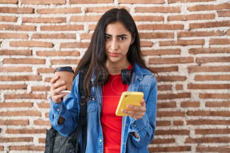 Téléchargez les photos : Young teenager girl wearing student backpack using smartphone skeptic and nervous, frowning upset because of problem. negative person. - en image libre de droit