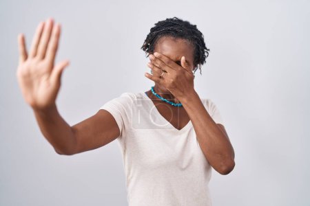 Photo for African woman with dreadlocks standing over white background covering eyes with hands and doing stop gesture with sad and fear expression. embarrassed and negative concept. - Royalty Free Image