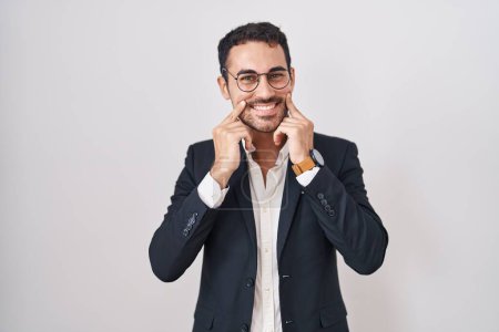 Téléchargez les photos : Bel homme d'affaires hispanique debout sur fond blanc souriant avec la bouche ouverte, les doigts pointant et forçant sourire joyeux - en image libre de droit