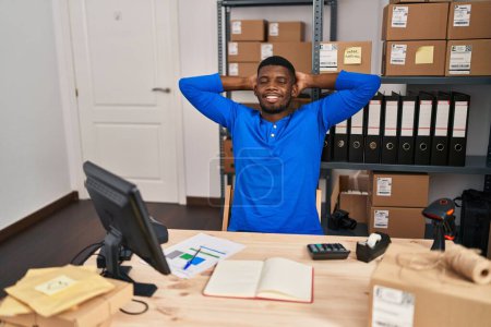 Téléchargez les photos : Jeune homme afro-américain ecommerce travailleur d'affaires détendu avec les mains sur la tête au bureau - en image libre de droit