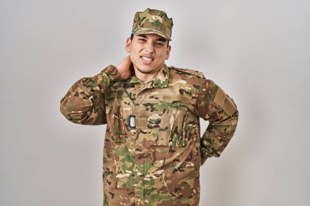 Photo for Young arab man wearing camouflage army uniform suffering of neck ache injury, touching neck with hand, muscular pain - Royalty Free Image