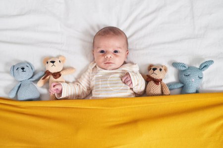 Photo for Adorable caucasian baby lying on bed with dolls at bedroom - Royalty Free Image