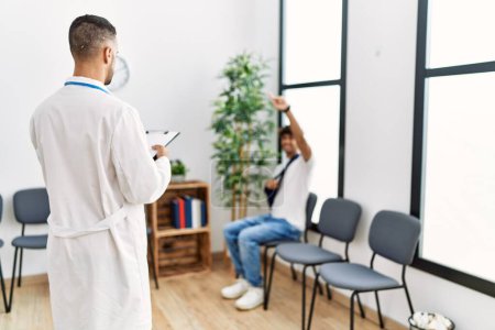 Téléchargez les photos : Deux hommes hispaniques médecin et patient à la salle d'attente de l'hôpital - en image libre de droit