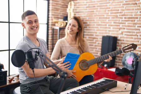 Foto de Músicos de hombre y mujer que tienen clase de guitarra clásica usando touchpad en el estudio de música - Imagen libre de derechos