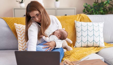 Téléchargez les photos : Mère et fils allaitant bébé télétravail à la maison - en image libre de droit