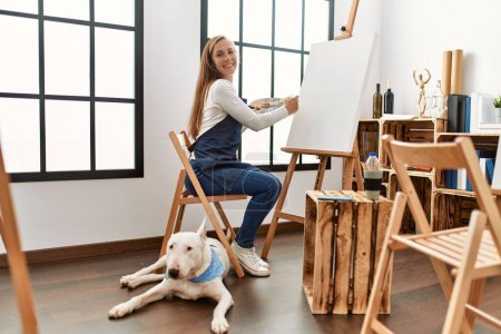 Photo for Young caucasian woman smiling confident drawing with dog at art studio - Royalty Free Image