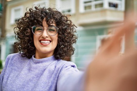 Téléchargez les photos : Jeune femme du Moyen-Orient souriant confiant faire selfie par la caméra à la rue - en image libre de droit