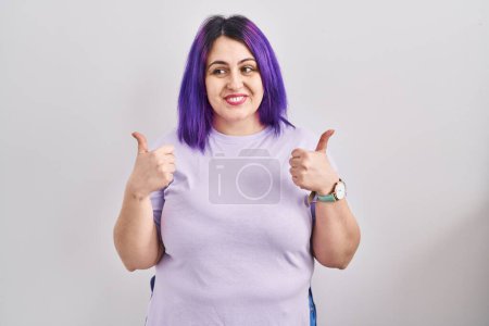Foto de Plus size woman wit purple hair standing over isolated background success sign doing positive gesture with hand, thumbs up smiling and happy. cheerful expression and winner gesture. - Imagen libre de derechos