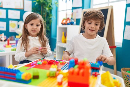 Téléchargez les photos : Frère et sœur jouant avec des blocs de construction assis sur la table à la maternelle - en image libre de droit