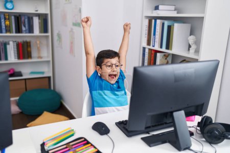 Foto de Adorable hispanic boy student using laptop with cheerful expression at classroom - Imagen libre de derechos