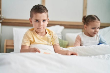 Foto de Dos niños leyendo el libro de cuentos sentados en la cama en el dormitorio - Imagen libre de derechos
