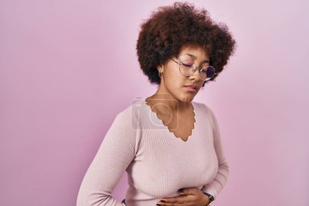 Foto de Mujer afroamericana joven de pie sobre fondo rosa con la mano en el estómago porque la indigestión, la enfermedad dolorosa sensación de malestar. concepto ache. - Imagen libre de derechos